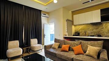Una sala de estar moderna con un sofá, una mesita de centro y una cocina al fondo.