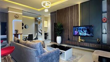 Una sala de estar moderna con un sofá gris, una mesa de centro y un televisor montado en la pared.