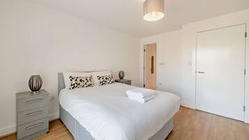 A bedroom with a bed, bedside tables, a lamp, and a door.