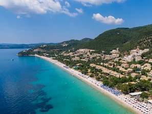 Eine Küstenstadt mit Strand, Gebäuden und einer hügeligen Kulisse.