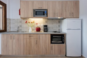 Uma cozinha moderna com armários de madeira, micro-ondas, cafeteira, torradeira e forno embutido.