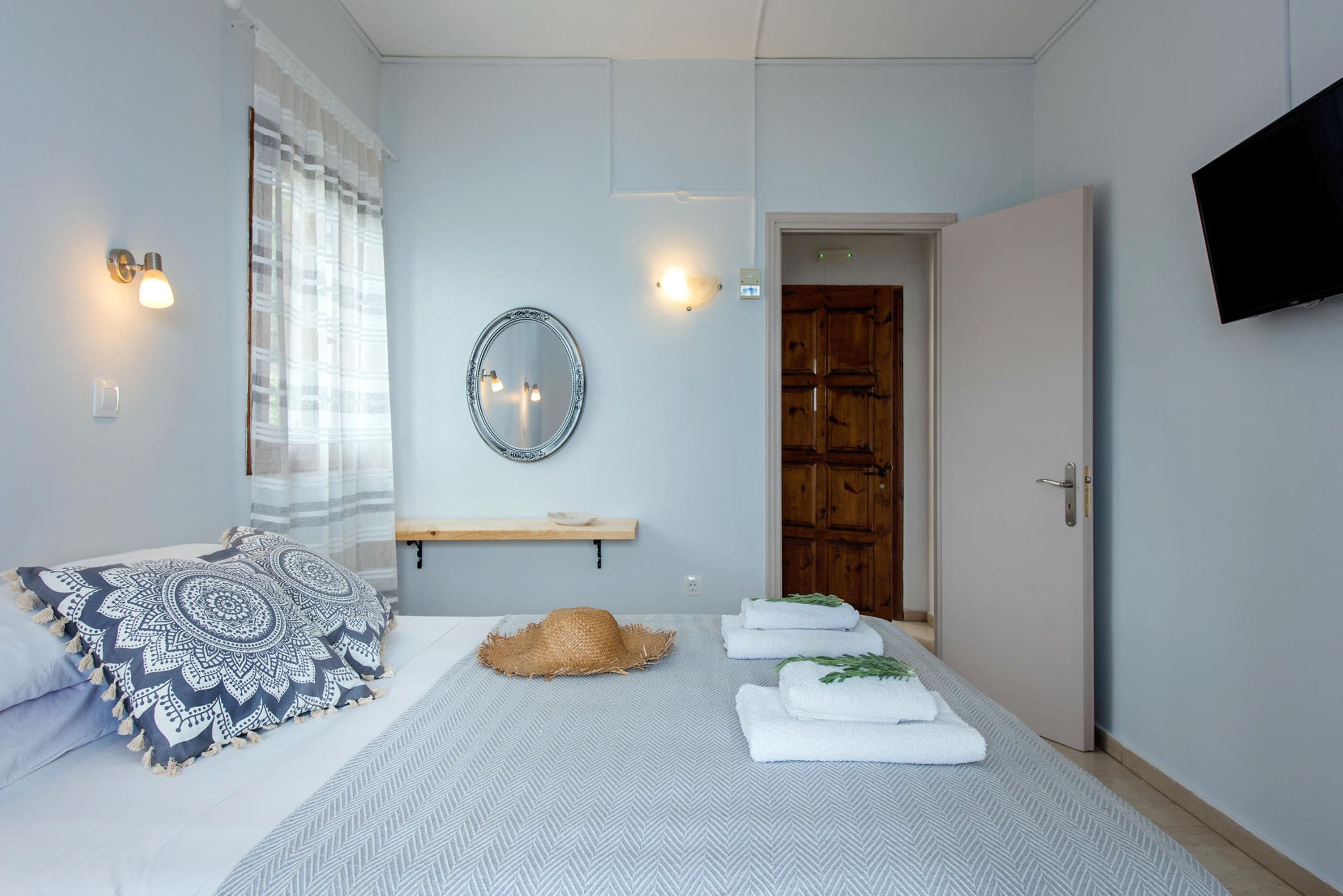 Una camera da letto con un letto, uno specchio, una televisione e una porta.
