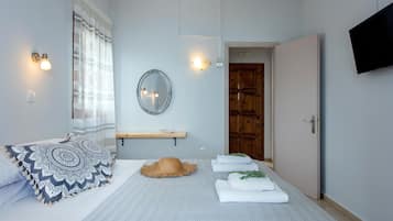 Una camera da letto con un letto, uno specchio, una televisione e una porta.