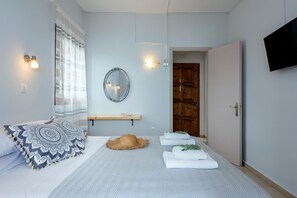 Ein Schlafzimmer mit Bett, Spiegel, Fernseher und Tür.