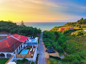 A coastal property with a swimming pool, a red-roofed building, and a view of the sea. - Indemela Corfu Lodge  (Karousades)