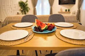 A dining table with four plates, a blue plate with fruit, and a fork on each side. - Indemela Corfu Lodge  (Karousades)