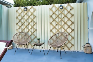 A patio area with two wicker chairs, a small table, and a decorative lantern. - Indemela Corfu Lodge  (Karousades)