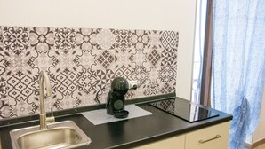 Cocina con mostrador negro moderno, pileta de acero inoxidable y azulejos decorativos en la pared.