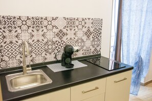 A kitchen with a modern black countertop, a stainless steel sink, and patterned backsplash tiles. - Mimì's House: Comfort in the Medieval Village of Nettuno (Nettuno)