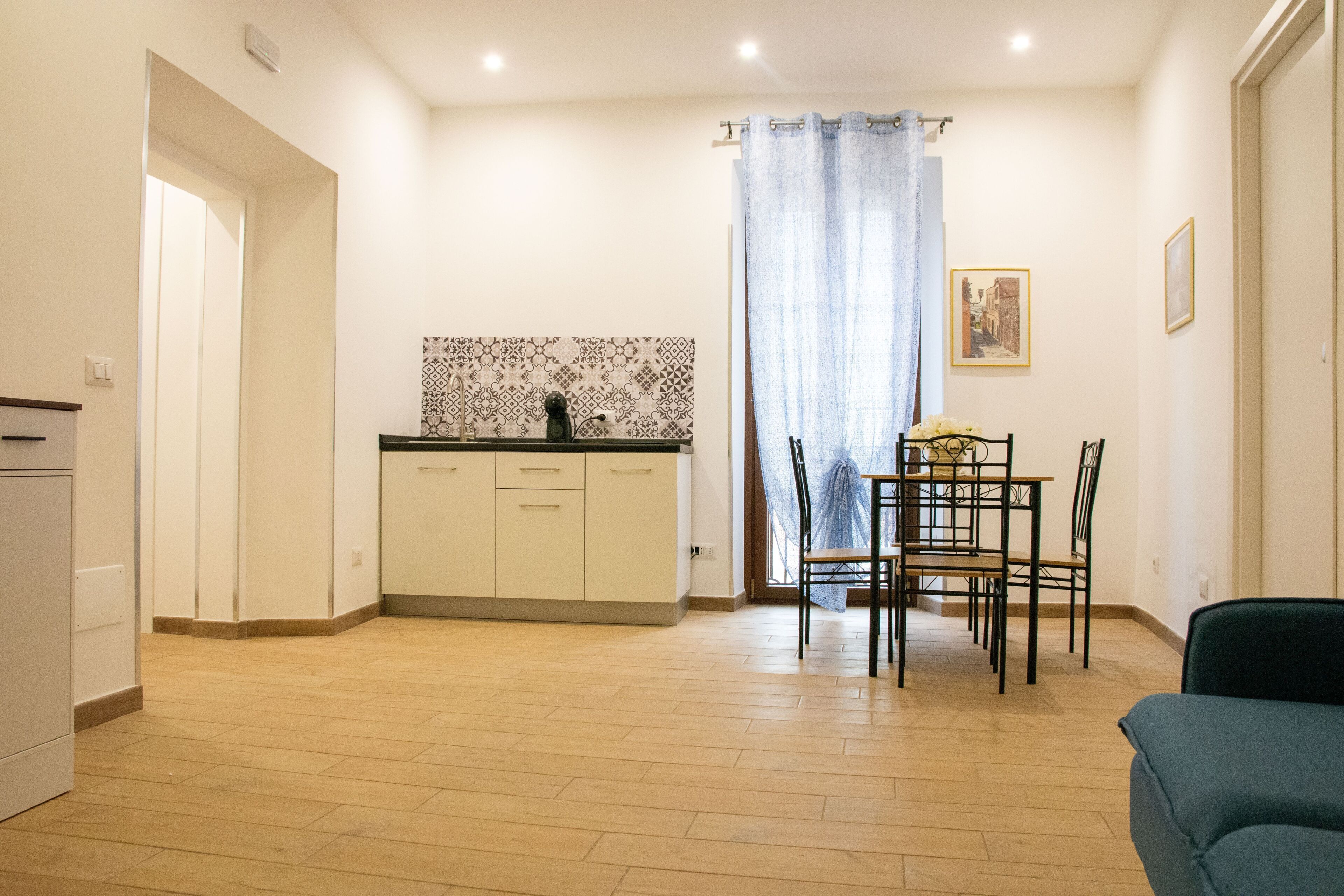 A compact kitchen with a tiled backsplash, a dining area with a table and chairs, and a small seating area with a sofa.