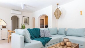 A modern living room with a light blue sofa, a wooden coffee table, and a hanging light fixture. - PALMERAS DEL MAR Villa by Abahana Villas (Teulada)