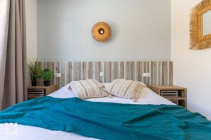 A bedroom with a bed, a wall-mounted circular light fixture, and a wooden headboard. - PALMERAS DEL MAR Villa by Abahana Villas (Teulada)