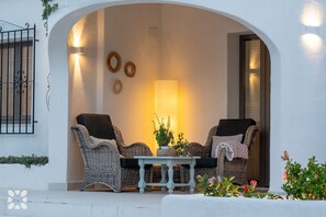 Ein Sitzbereich im Freien mit Korbstühlen, einem Tisch und einer Lampe.