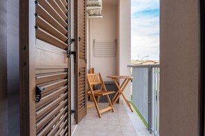 Ein Balkon mit Holztür, Klapptisch und zwei Stühlen.