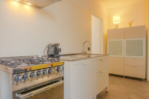 Eine kleine Küche mit Gaskochfeld, Kaffeemaschine und Spüle.