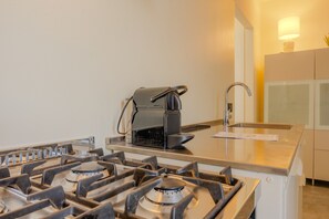 A kitchen with a gas stove, a coffee machine, and a sink. - SG Family - Il Meriggio (Peschiera del Garda)