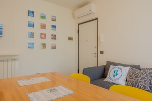 Ein Zimmer mit einem Holztisch, einem Sofa mit Kissen und einer Tür.