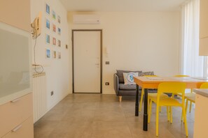 A dining area with a table, chairs, and a sofa. There is a door and a radiator on the wall. - SG Family - Il Meriggio (Peschiera del Garda)