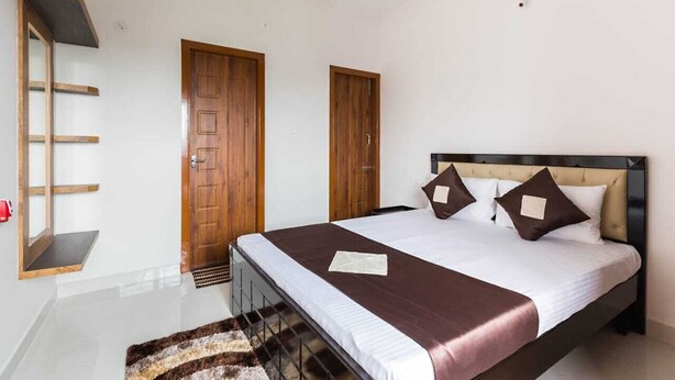 Un dormitorio con cama, dos puertas, un estante de madera y una alfombra pequeña.