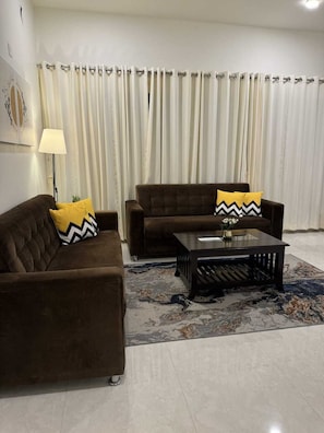 A living room with two brown sofas, a coffee table, and a patterned rug.