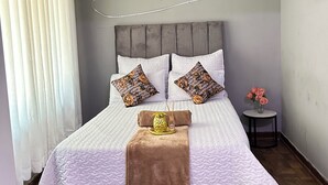Ein Schlafzimmer mit Bett, Kissen, einem Nachttisch und einer Wandleuchte.