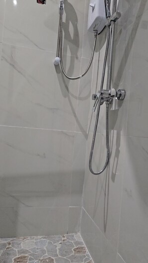 A shower area with a tiled wall and floor, a handheld showerhead, and a wall-mounted control unit. - Beautiful 1-bedroom bed & breakfast in charming Harare (Harare)