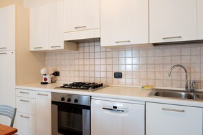 A compact kitchen with white cabinets, a gas stove, a dishwasher, and a sink. - SG Family - Park Everywhere Apartment (Castelnuovo del Garda)
