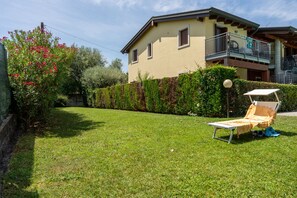 A house with a well-maintained lawn, a lounge chair, and a balcony. - SG Family - Park Everywhere Apartment (Castelnuovo del Garda)