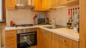 Una cocina con armarios de madera, estufa a gas, microondas y un lavamanos.