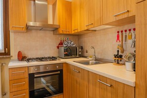 A kitchen with wooden cabinets, a gas stove, a microwave, and a sink. - SG Family - Casa Bertolini (Castelnuovo del Garda)