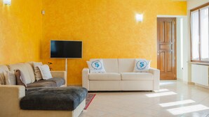 Una sala de estar con un conjunto de sofás, un televisor de pantalla plana y una puerta de madera.