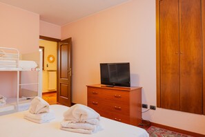 A hotel room with a bunk bed, a wooden dresser with a television, and a door leading to another room. - SG Family - Casa Bertolini (Castelnuovo del Garda)