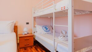 Habitación con literas, una mesita de noche de madera, una lámpara y un reloj.