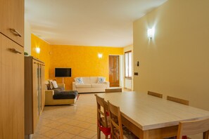 A room with a dining table, a sofa, and a TV. - SG Family - Casa Bertolini (Castelnuovo del Garda)