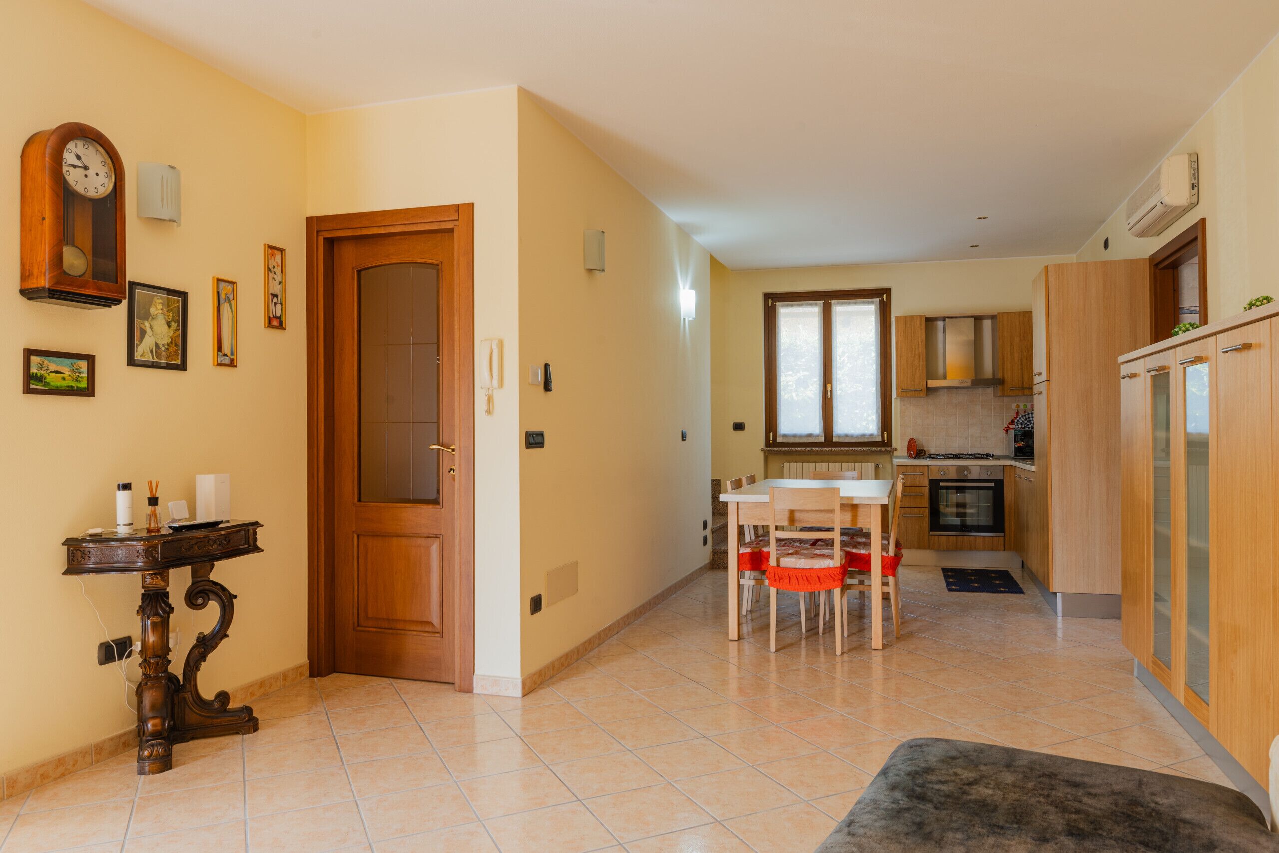 A modern kitchen with wooden cabinets, a dining table with chairs, and a built-in oven.