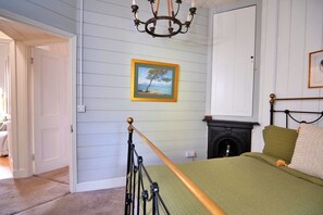 A bedroom with a bed, a fireplace, a chandelier, and a framed painting on the wall. - Holiday Home Near Dolgellau (Dolgellau)