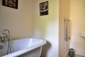 A bathroom with a white bathtub, a towel rack, and a small trash bin. - Holiday Home Near Dolgellau (Dolgellau)