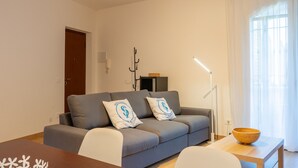 Ett modernt vardagsrum med en soffa, två kuddar, en träskål på ett sidobord och en lampa.