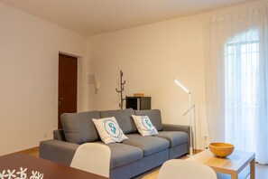 Ein modernes Wohnzimmer mit einer Couch, zwei Kissen, einer Holzschüssel auf einem Beistelltisch und einer Lampe.