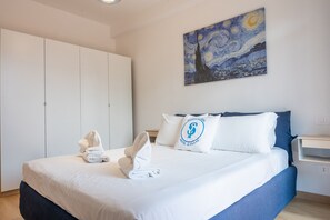 Ein Hotelzimmer mit Bett, einem Bild an der Wand und einem Kopfkissen mit einem Logo.