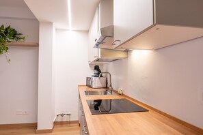 Eine moderne Küche mit Holzausziehtisch, Edelstahlspüle und einem eingebauten Backofen.