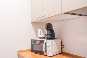 Eine Küchenzeile mit einer weißen Mikrowelle, einer Kaffeemaschine und einem Toaster auf einer Holz Arbeitsplatte.