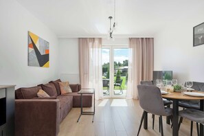 Ein modernes Wohnzimmer mit einem braunen Sofa, einem Glastisch und einem Essbereich mit Tisch für zwei Personen.