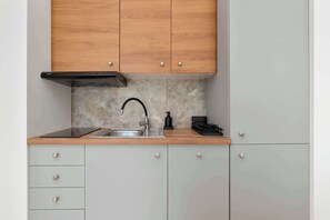 Eine moderne Küche mit Spüle aus Edelstahl, Holzschränken und einer schwarzen Dunstabzugshaube.