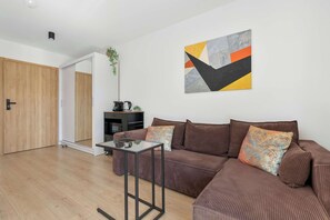 A modern living room with a brown sofa, a glass coffee table, and a painting on the wall. - Brown Apartment with Garden | Desk | Parking (Jastrzębia Góra)