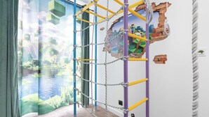 Ein Zimmer mit einer Kletterwand, einem Fenster mit Blick auf ein Gewässer und einer Wand mit einem Minecraft-Wandbild.