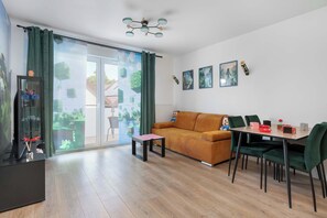 Ein modernes Wohnzimmer mit einer Couch, einem Esstisch mit Stühlen und einer Glastür, die auf einen Balkon führt.