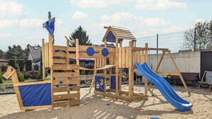 Eine Holzspielanlage mit Rutsche und Kletterelementen.
