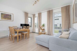 Ein modernes Wohnzimmer mit grauem Sofa, einem Holzesstisch und Stühlen.