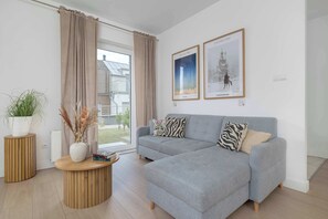 Ein modernes Wohnzimmer mit einem grauen Ecksofa, einem Holztisch und zwei gerahmten Kunstwerken an der Wand.